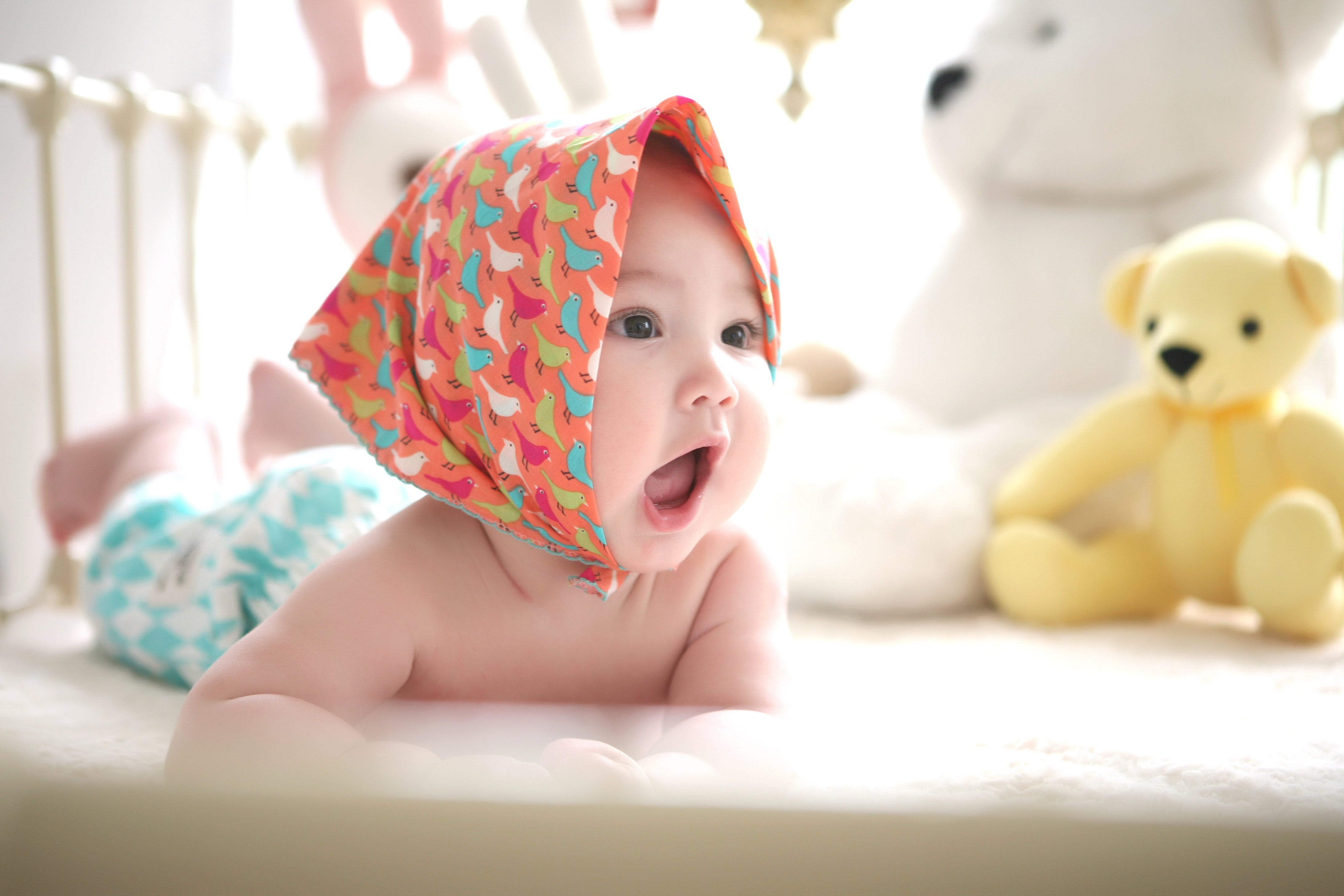 Bebé sonriendo en su cuna llena de peluches